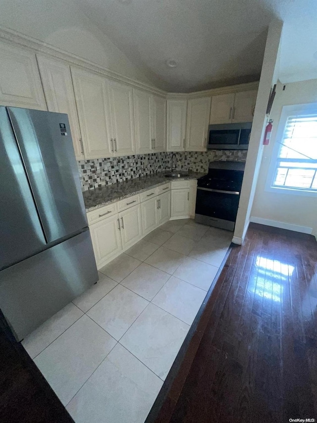 kitchen featuring white cabinets, light hardwood / wood-style floors, appliances with stainless steel finishes, and tasteful backsplash