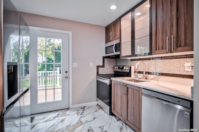 6 George Ave, Hicksville, NY 11801 - kitchen featuring appliances with stainless steel finishes, decorative backsplash, glass insert cabinets, light stone counters, and light marble finish floors