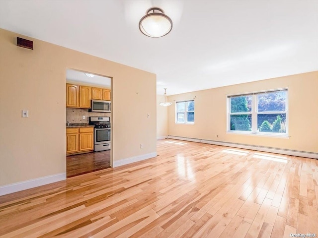 unfurnished living room with baseboard heating and light hardwood / wood-style flooring