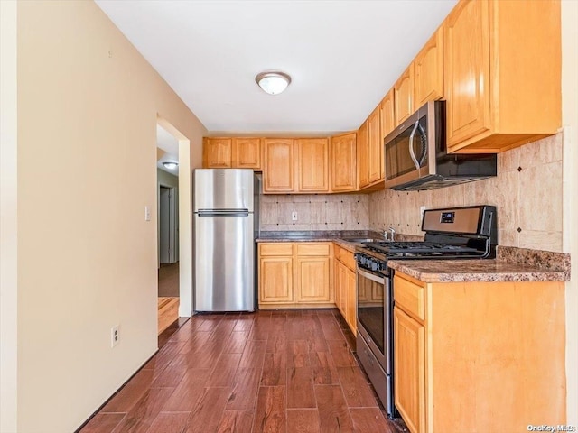 kitchen featuring appliances with stainless steel finishes, backsplash, dark wood-type flooring, and light brown cabinets