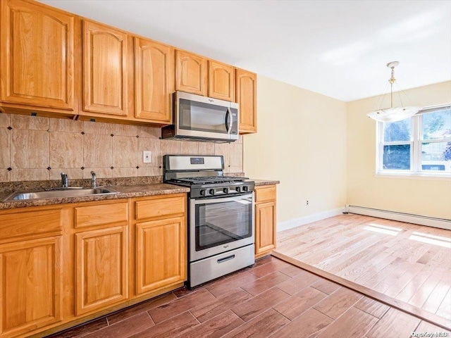 kitchen featuring appliances with stainless steel finishes, dark hardwood / wood-style flooring, sink, pendant lighting, and a baseboard radiator