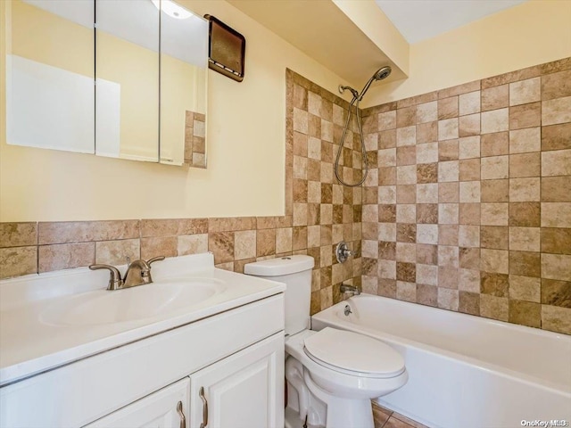 full bathroom with vanity, tile patterned floors, tiled shower / bath combo, toilet, and tile walls