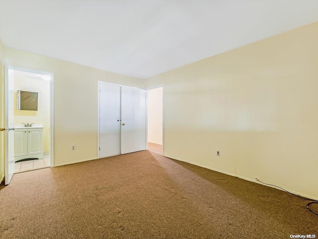 unfurnished bedroom featuring carpet flooring, ensuite bathroom, and sink