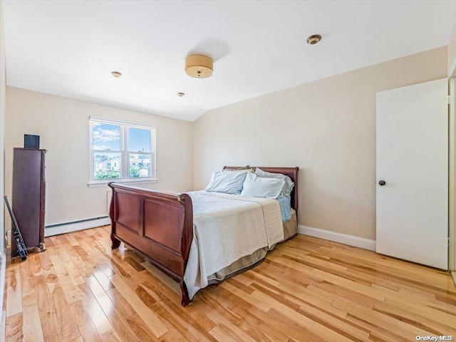 bedroom with light hardwood / wood-style flooring and a baseboard heating unit