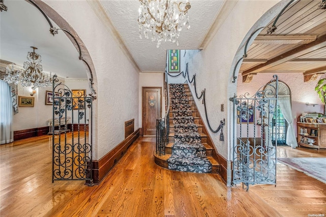 stairs featuring a textured ceiling, crown molding, a notable chandelier, and hardwood / wood-style flooring