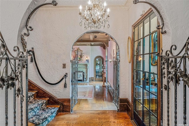 entryway with a chandelier, a textured ceiling, hardwood / wood-style flooring, and crown molding