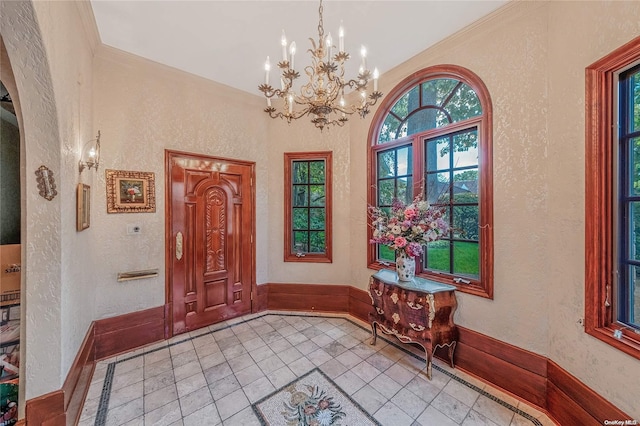 entryway featuring light tile patterned floors, an inviting chandelier, and crown molding