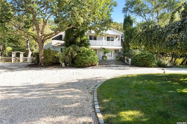 view of front of house with a balcony, a porch, and a front yard