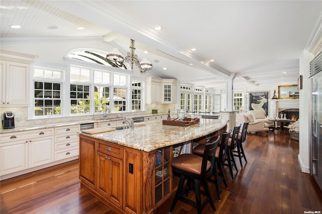 kitchen with a large island with sink, lofted ceiling with beams, tasteful backsplash, and plenty of natural light