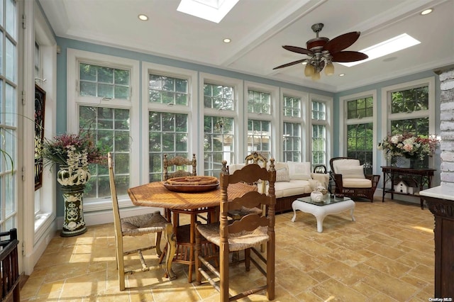 sunroom featuring beam ceiling, a skylight, ceiling fan, and a healthy amount of sunlight