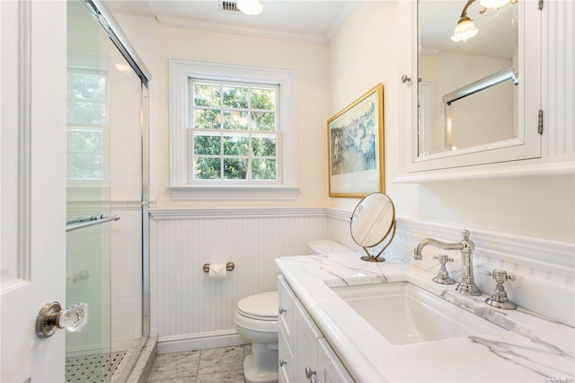 bathroom with vanity, toilet, a shower with shower door, and crown molding