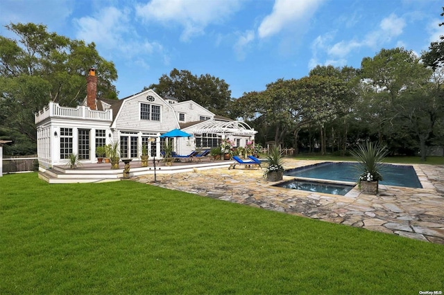 rear view of house with a pool with hot tub, a patio area, a yard, and a balcony