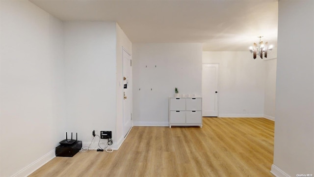 laundry area with light hardwood / wood-style floors and a chandelier