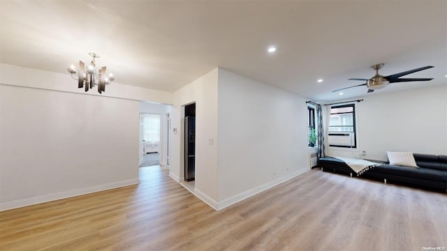 living room featuring ceiling fan with notable chandelier and light wood-type flooring