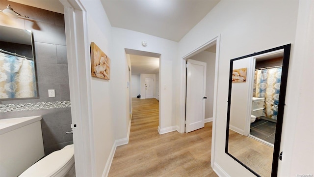 corridor featuring light hardwood / wood-style floors and tile walls