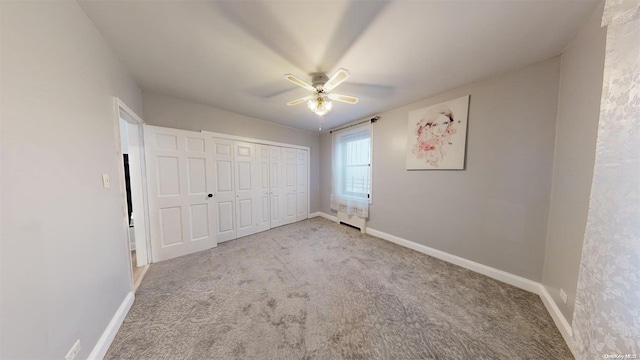 unfurnished bedroom with radiator, ceiling fan, a closet, and light carpet