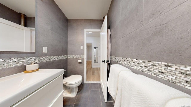 bathroom with tile patterned flooring, vanity, toilet, and tile walls