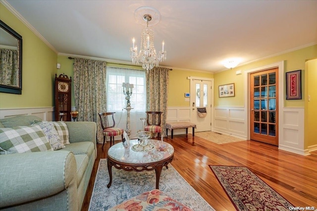 living room featuring a notable chandelier, wood-type flooring, and crown molding