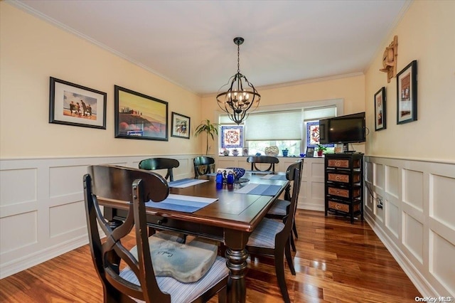 dining space featuring wood-type flooring, ornamental molding, and a chandelier