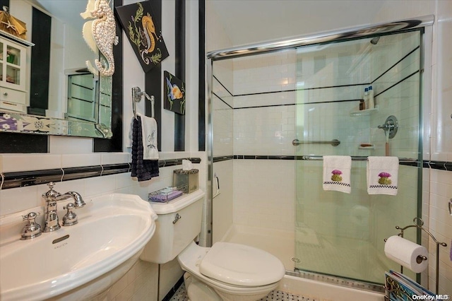 bathroom with an enclosed shower, toilet, tile walls, and sink