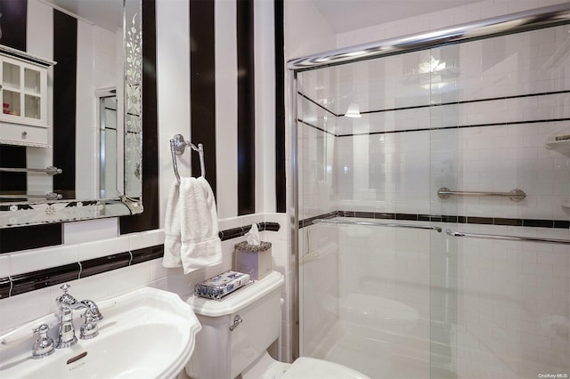 bathroom with tasteful backsplash, sink, tile walls, toilet, and a shower with shower door