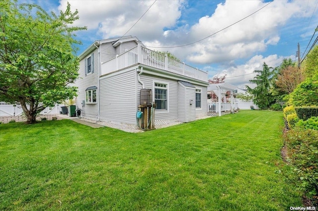 rear view of property with a yard and a balcony