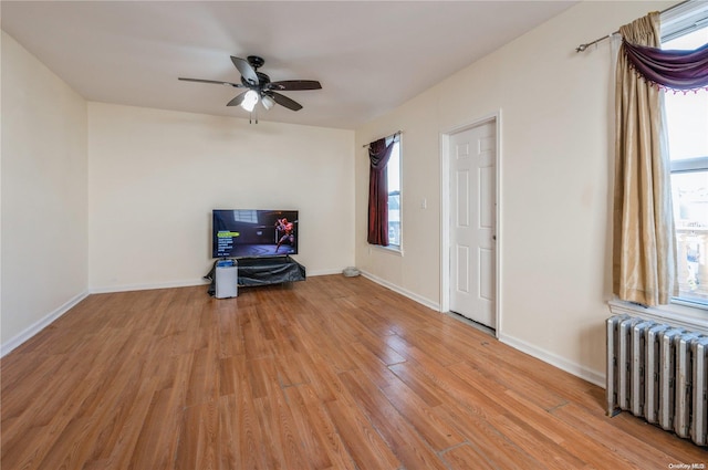 empty room featuring radiator heating unit, light hardwood / wood-style floors, and ceiling fan