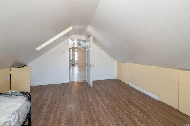 additional living space with lofted ceiling with skylight and dark wood-type flooring