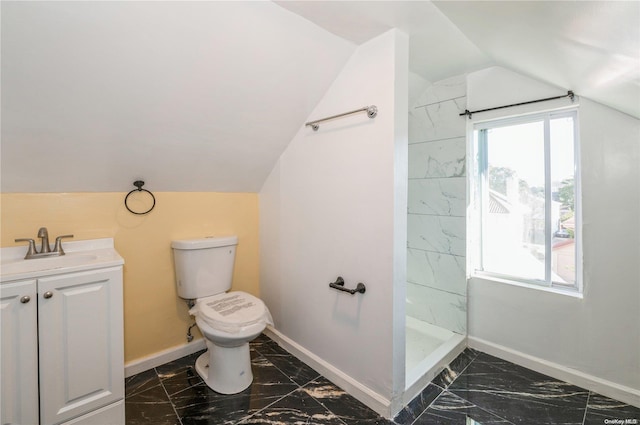 bathroom featuring a tile shower, vanity, toilet, and lofted ceiling