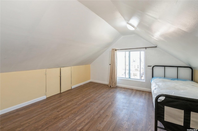 unfurnished bedroom featuring dark hardwood / wood-style flooring and lofted ceiling