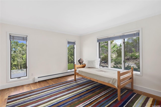 bedroom with wood-type flooring and a baseboard heating unit