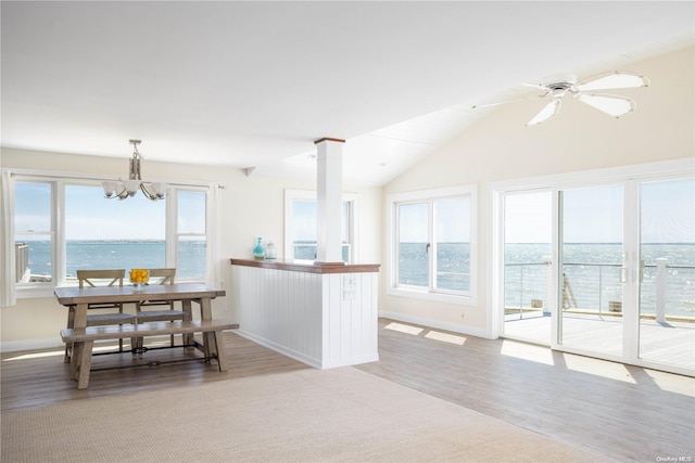 kitchen with light wood-type flooring, ceiling fan with notable chandelier, a water view, hanging light fixtures, and lofted ceiling