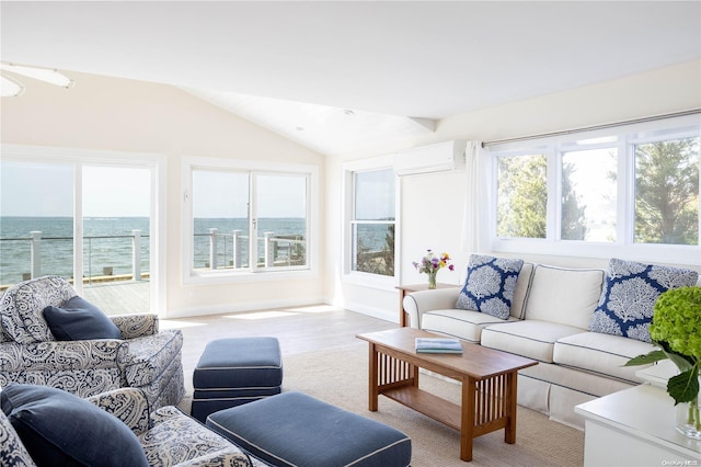 living room with an AC wall unit, a water view, and vaulted ceiling