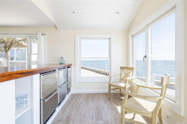 kitchen featuring stainless steel refrigerator, a water view, lofted ceiling, and light wood-type flooring