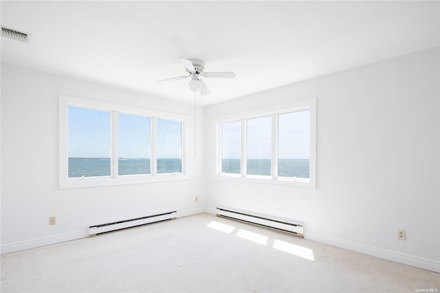 spare room featuring a baseboard radiator, ceiling fan, light colored carpet, and a water view