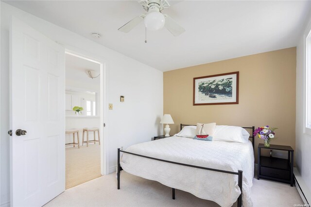 4235 Camp Mineola Rd, Mattituck, NY 11952 - bedroom with light colored carpet, baseboard heating, a ceiling fan, and baseboards