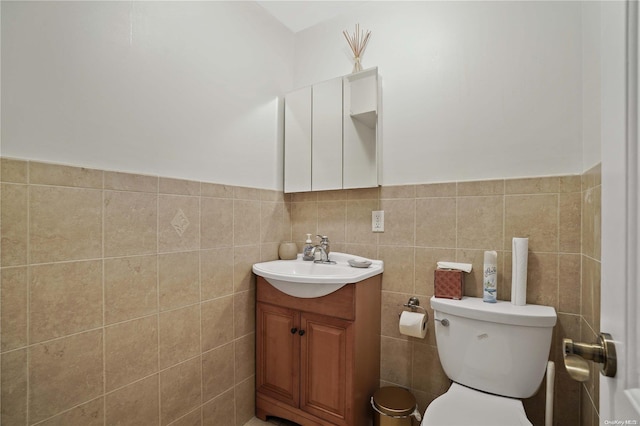 bathroom featuring vanity, toilet, and tile walls