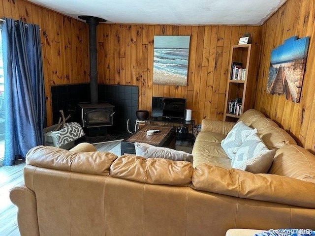 living room with a wood stove and wooden walls