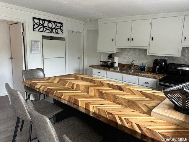 kitchen featuring decorative backsplash, stove, sink, tile countertops, and white cabinets