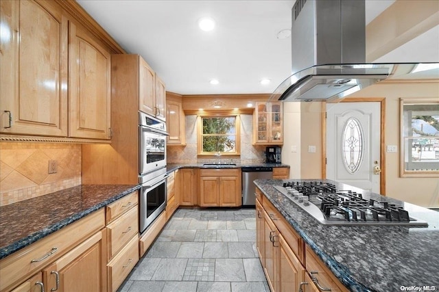 kitchen featuring dark stone counters, island exhaust hood, appliances with stainless steel finishes, and tasteful backsplash