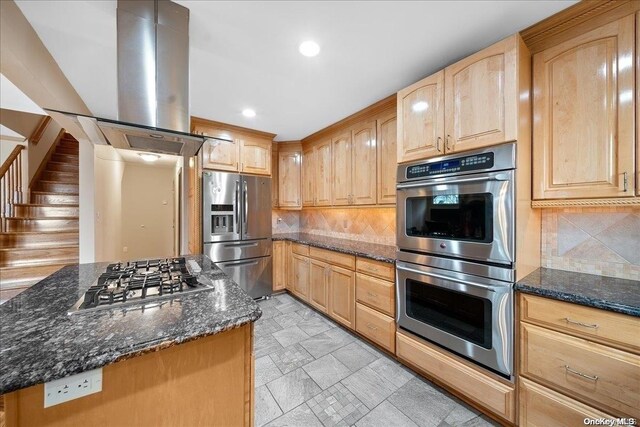 kitchen featuring appliances with stainless steel finishes, island range hood, and dark stone countertops