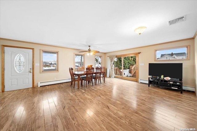 dining space with crown molding, baseboard heating, and light hardwood / wood-style flooring