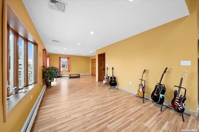 workout room featuring light hardwood / wood-style floors and a baseboard heating unit