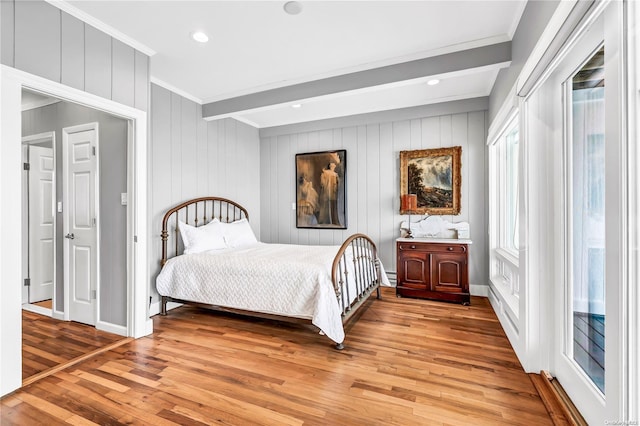 bedroom with beam ceiling, crown molding, a baseboard heating unit, and light wood-type flooring