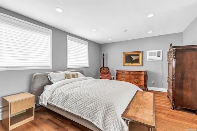 bedroom with hardwood / wood-style floors and a wall unit AC