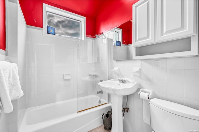 bathroom featuring tiled shower / bath combo, tile walls, and toilet