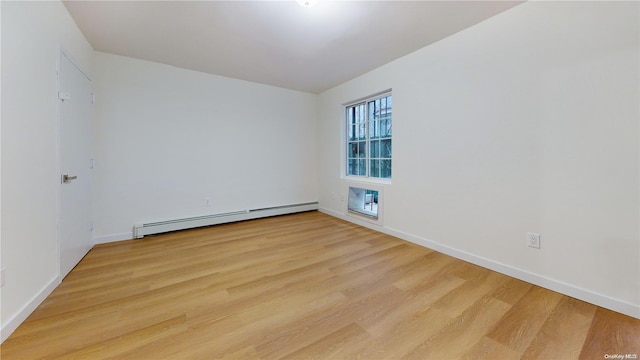 empty room featuring a baseboard radiator and light wood-type flooring