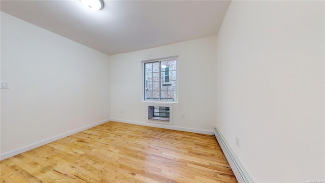 empty room featuring light wood-type flooring, baseboard heating, and heating unit