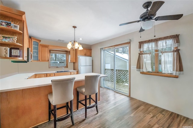 kitchen featuring sink, light hardwood / wood-style flooring, a kitchen breakfast bar, kitchen peninsula, and white fridge