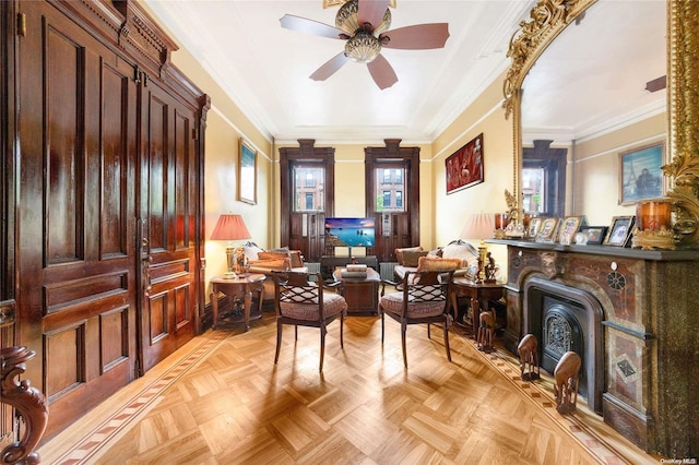 sitting room with ceiling fan, ornamental molding, a fireplace, and light parquet flooring